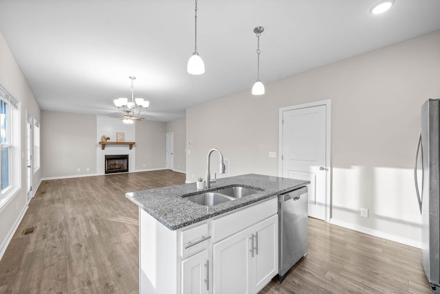 kitchen featuring visible vents, stainless steel dishwasher, a sink, a fireplace, and fridge