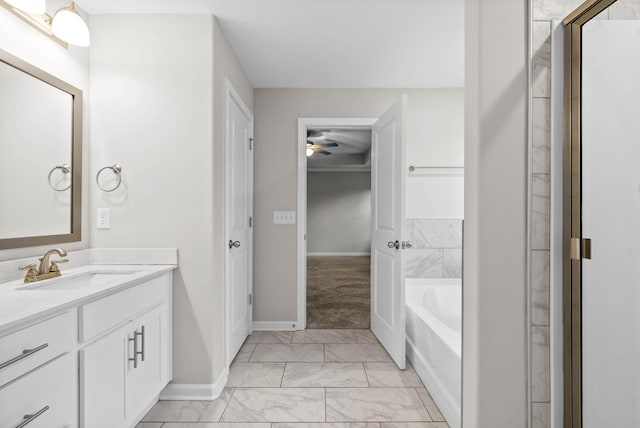 bathroom featuring marble finish floor, a ceiling fan, vanity, baseboards, and a garden tub