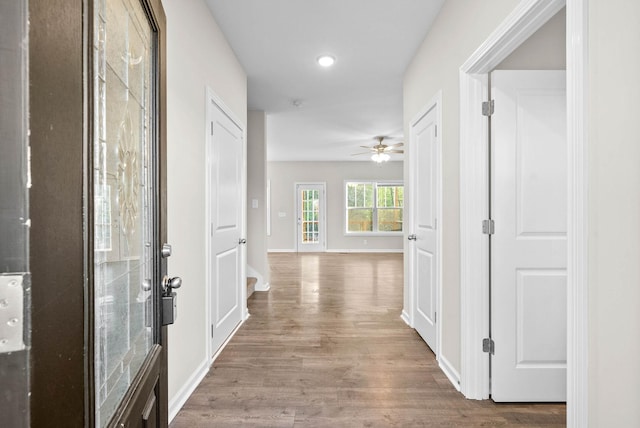 hallway featuring baseboards, wood finished floors, and recessed lighting