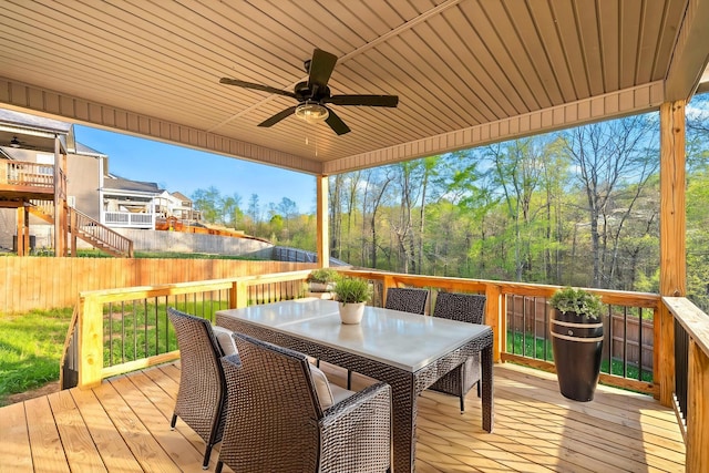 wooden terrace with outdoor dining area, fence, and ceiling fan