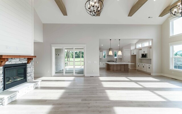7295 NW Hwy, Fairview, TN 37062 - unfurnished living room with a chandelier, plenty of natural light, high vaulted ceiling, light wood-type flooring, and a stone fireplace