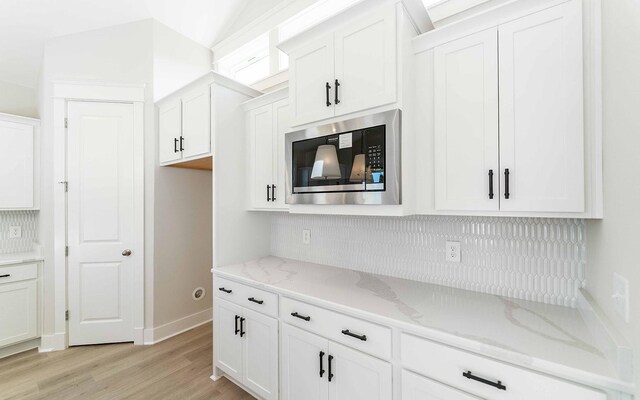 7295 NW Hwy, Fairview, TN 37062 - kitchen with stainless steel microwave, light wood-style flooring, decorative backsplash, and white cabinets