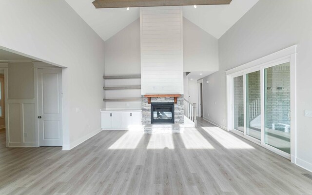 7295 NW Hwy, Fairview, TN 37062 - unfurnished living room featuring high vaulted ceiling, baseboards, a glass covered fireplace, and light wood finished floors