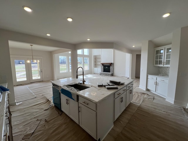 kitchen with white cabinets, a kitchen island with sink, tasteful backsplash, open floor plan, and dishwasher