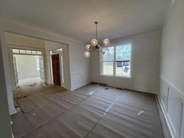 unfurnished dining area with a decorative wall, a chandelier, a wainscoted wall, ornamental molding, and visible vents