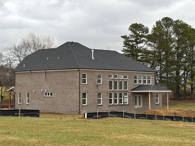 back of property with fence, a lawn, and roof with shingles