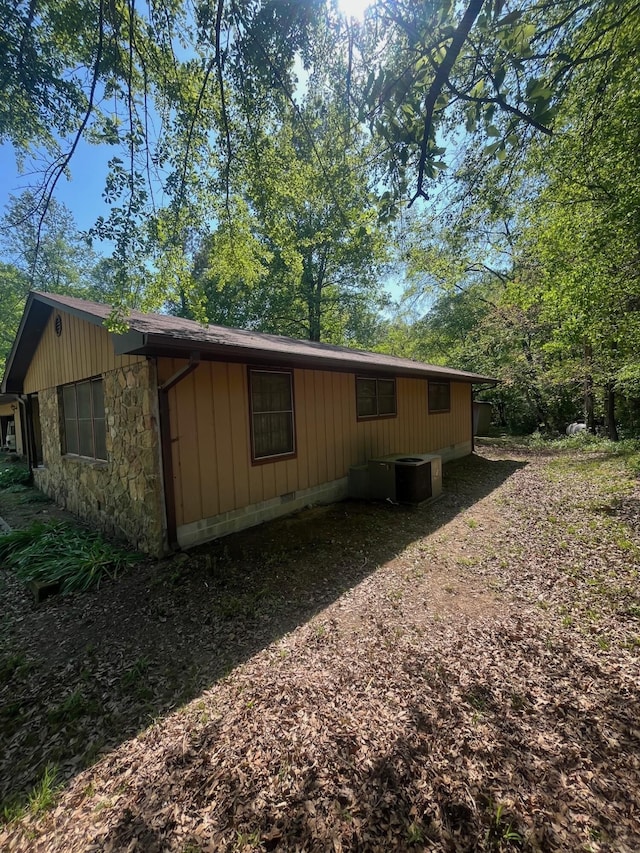 view of property exterior featuring central air condition unit and stone siding