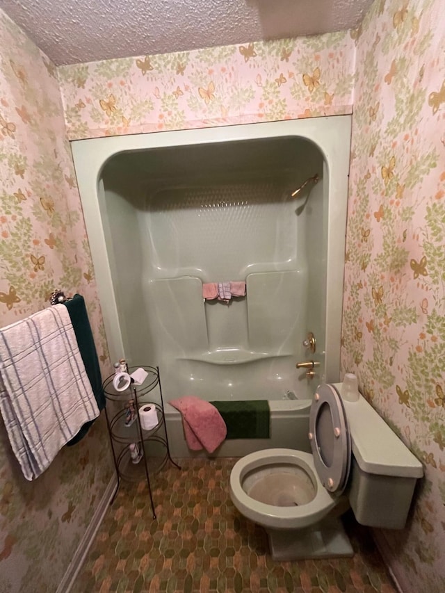 bathroom featuring toilet, a textured ceiling, and wallpapered walls