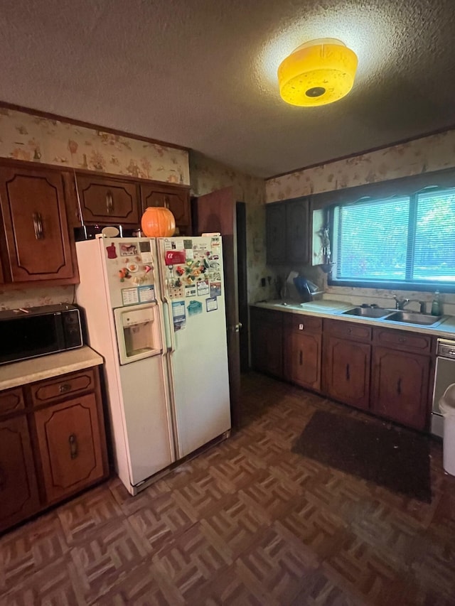 kitchen with a sink, white refrigerator with ice dispenser, and light countertops