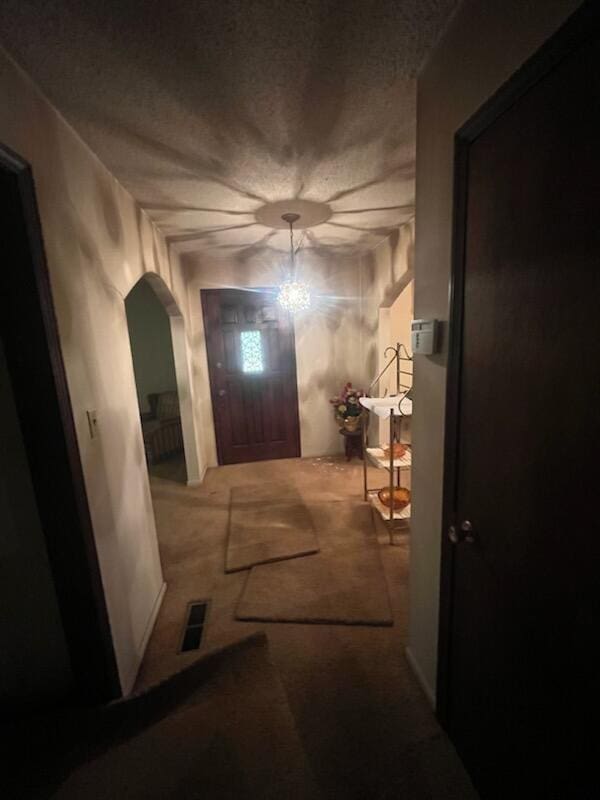 corridor with arched walkways, carpet floors, and visible vents