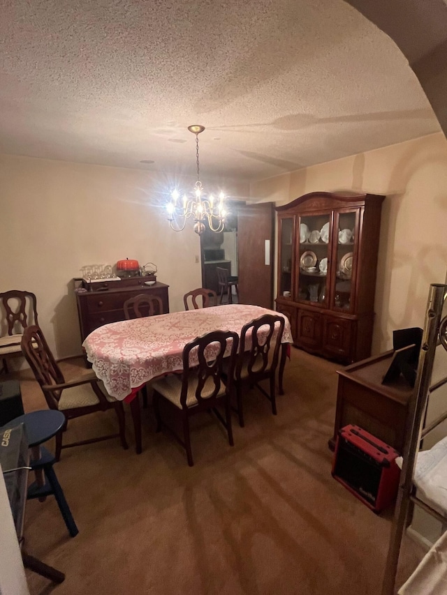dining room featuring a notable chandelier, carpet flooring, and a textured ceiling