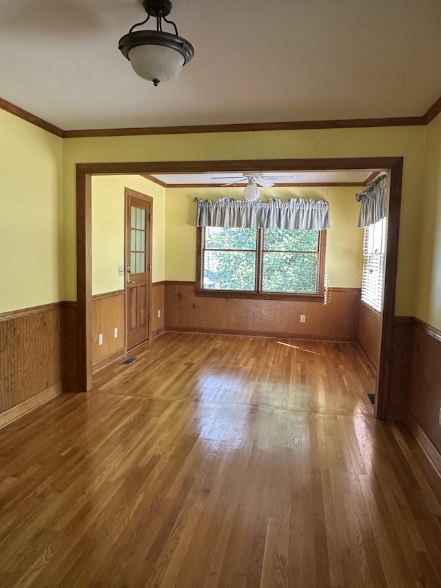 unfurnished room with a wainscoted wall, wood walls, and wood-type flooring