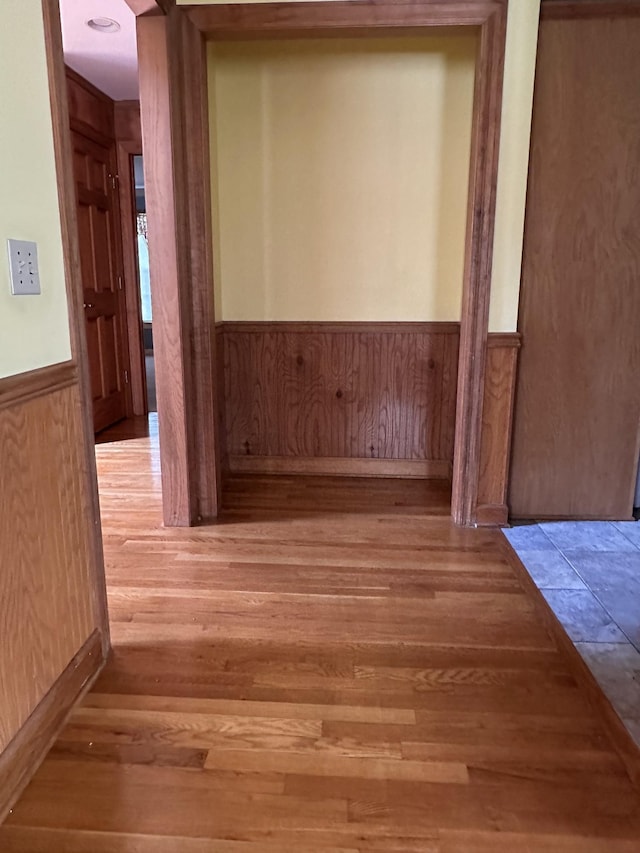 hall featuring wood finished floors, wood walls, and wainscoting