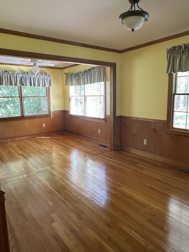 spare room featuring visible vents, a wainscoted wall, wood finished floors, and crown molding