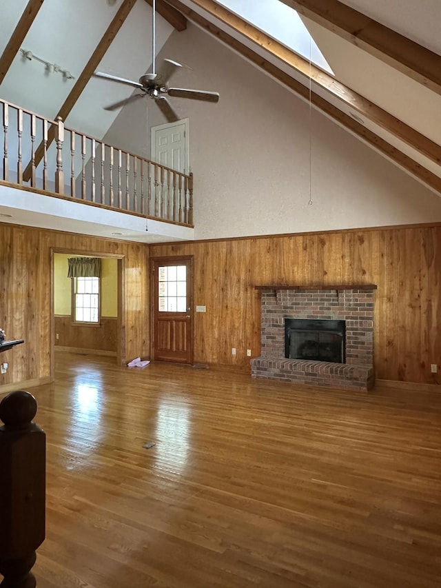 unfurnished living room with high vaulted ceiling, wood walls, wood finished floors, and beam ceiling