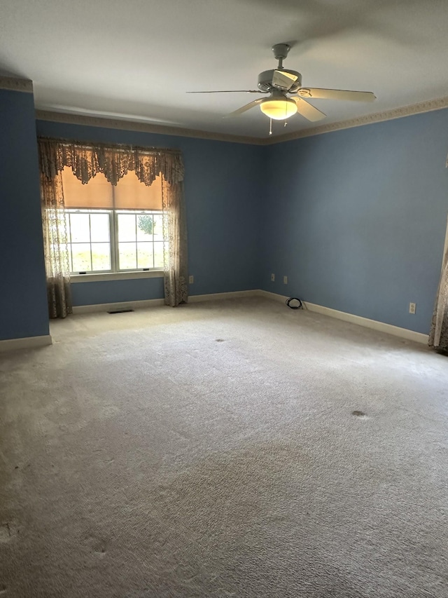 unfurnished room with visible vents, ornamental molding, baseboards, carpet flooring, and ceiling fan