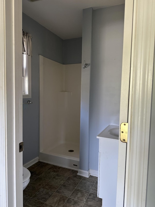 bathroom with baseboards, vanity, toilet, and a stall shower