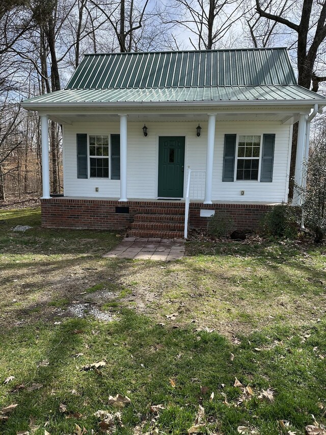 view of front facade featuring a front lawn, covered porch, and metal roof