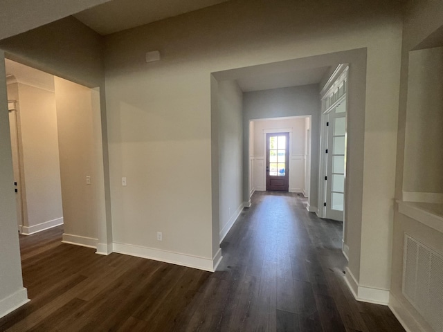 hallway with baseboards, dark wood-style flooring, and visible vents