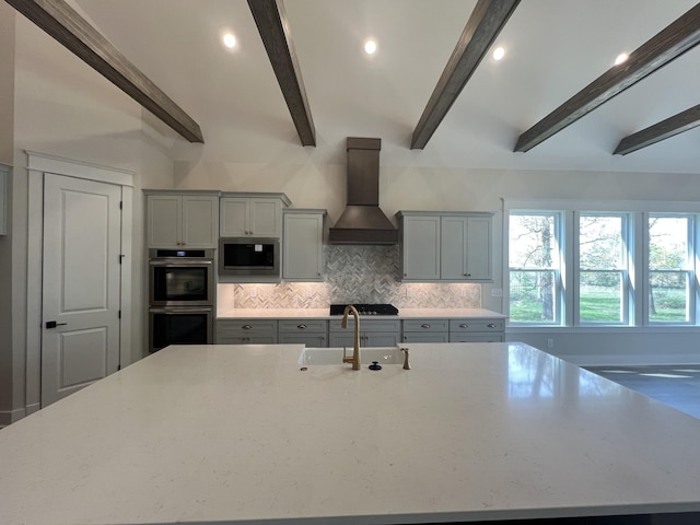 kitchen with gray cabinetry, a sink, appliances with stainless steel finishes, and premium range hood