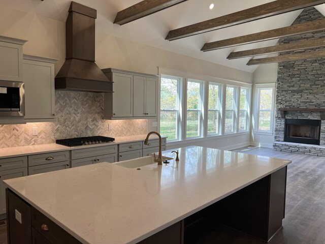kitchen featuring a sink, decorative backsplash, open floor plan, stainless steel appliances, and premium range hood