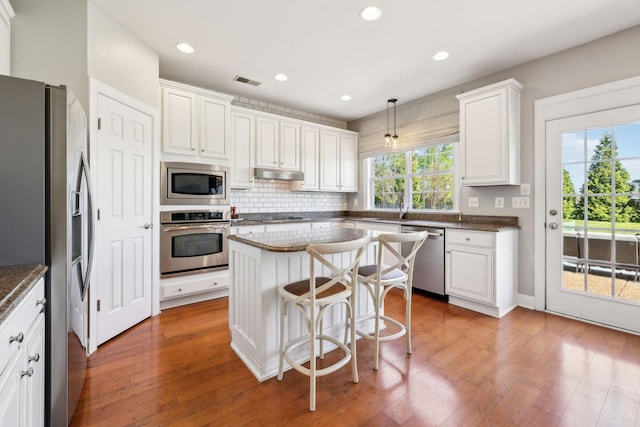 107 Jasmine Ct, Gallatin, TN 37066 - kitchen with appliances with stainless steel finishes, under cabinet range hood, decorative backsplash, white cabinetry, and light wood-type flooring