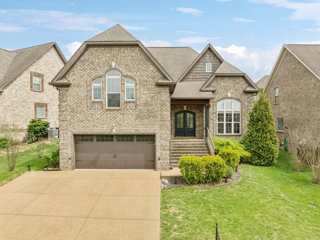 325 Midtown Trl, Mount Juliet, TN 37122 - french country style house featuring a front lawn, driveway, french doors, a garage, and brick siding