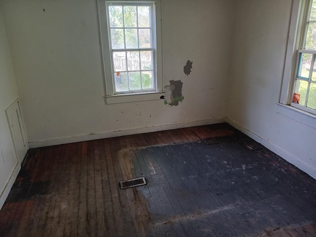 unfurnished room with baseboards, a wealth of natural light, and wood-type flooring