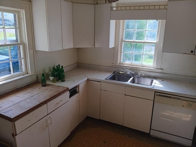 kitchen featuring dishwasher, light countertops, a sink, and white cabinetry
