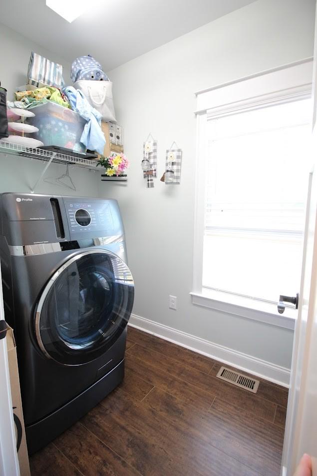 clothes washing area featuring baseboards, visible vents, wood finished floors, washer / clothes dryer, and laundry area