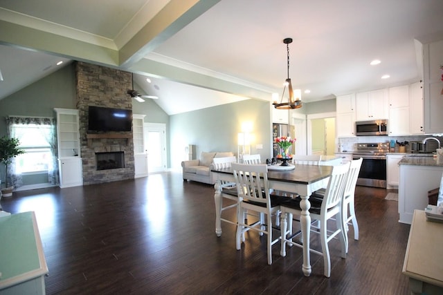dining space with recessed lighting, vaulted ceiling, a stone fireplace, dark wood-type flooring, and ceiling fan with notable chandelier