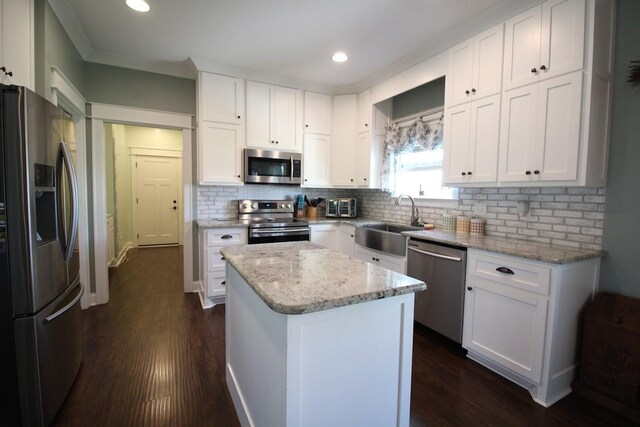 kitchen with a sink, stainless steel appliances, white cabinets, dark wood-style flooring, and a kitchen island