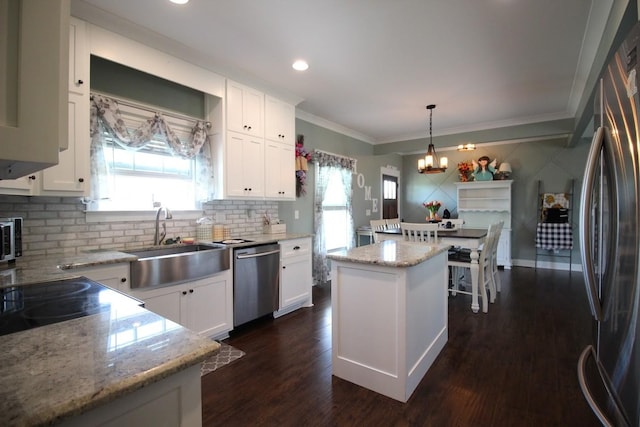 kitchen featuring white cabinets, stainless steel appliances, an inviting chandelier, a sink, and a kitchen island
