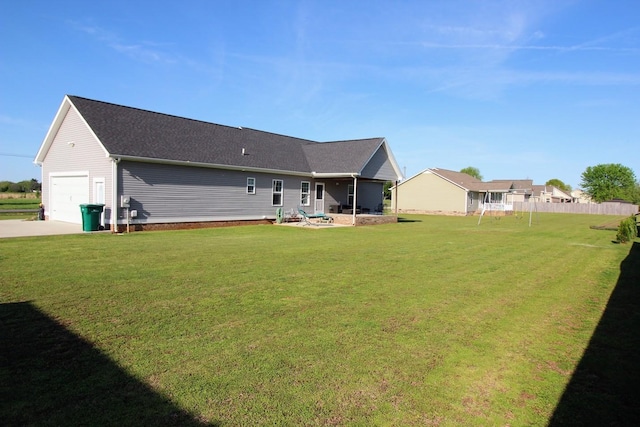 back of house with a yard, driveway, and a shingled roof