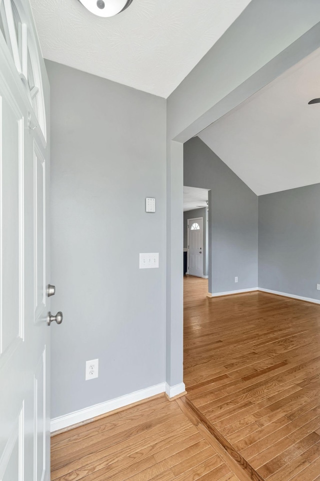 entrance foyer featuring baseboards, vaulted ceiling, and light wood-style flooring