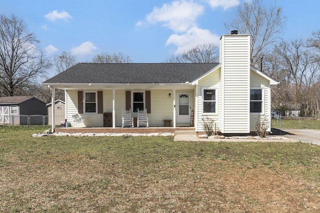 single story home with a chimney, fence, covered porch, roof with shingles, and a front yard