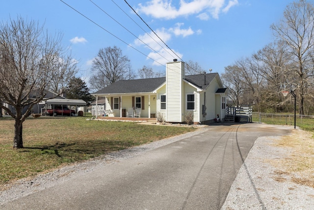 view of front of home featuring a porch, driveway, a chimney, and a front yard