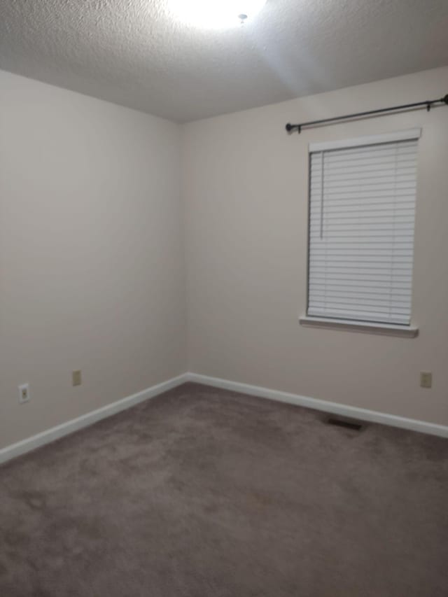 carpeted spare room featuring baseboards