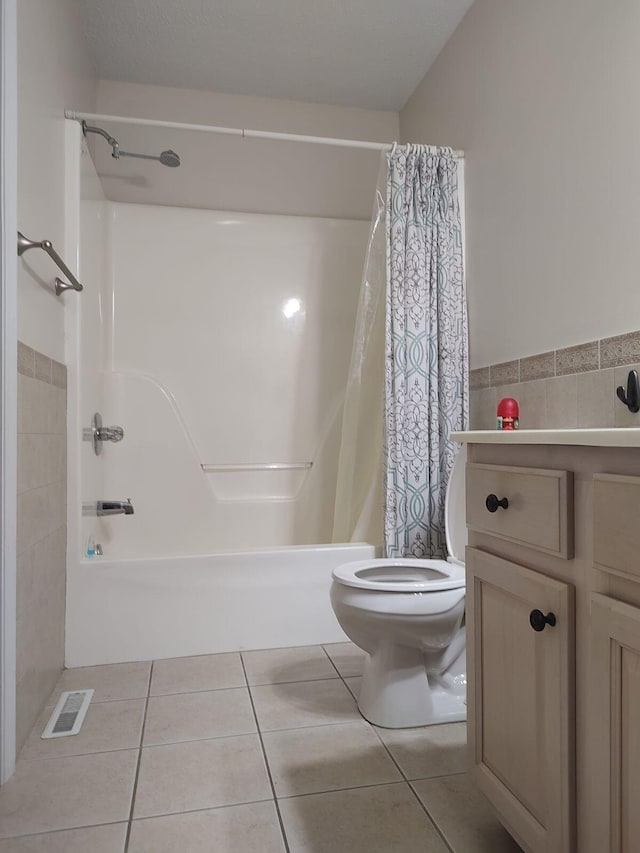 bathroom featuring tile patterned flooring, tile walls, toilet, visible vents, and shower / tub combo