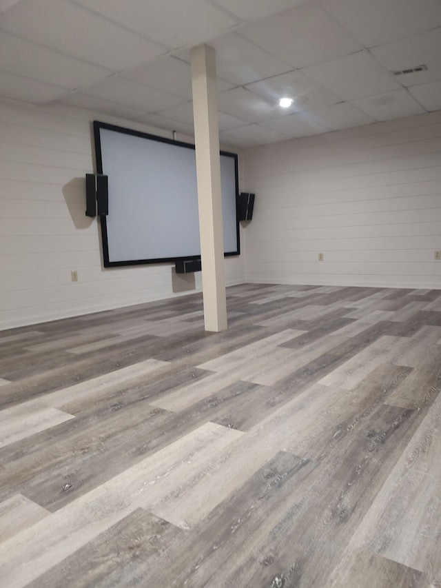 finished below grade area with wood finished floors, visible vents, and a drop ceiling