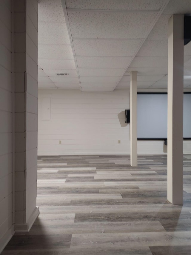 finished below grade area with a paneled ceiling and wood finished floors