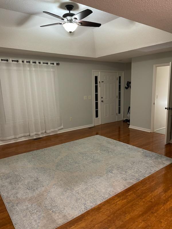 empty room featuring baseboards, wood finished floors, and a ceiling fan