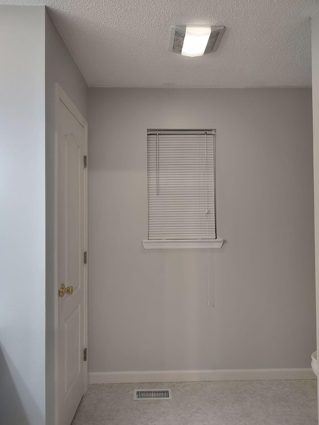 empty room with a textured ceiling, visible vents, and baseboards