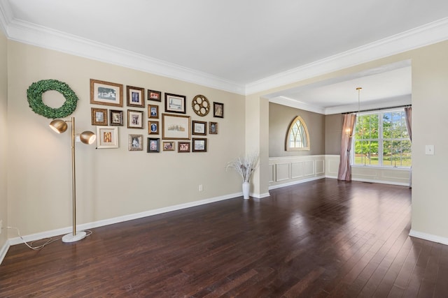 unfurnished living room featuring dark wood-type flooring, ornamental molding, baseboards, and a chandelier