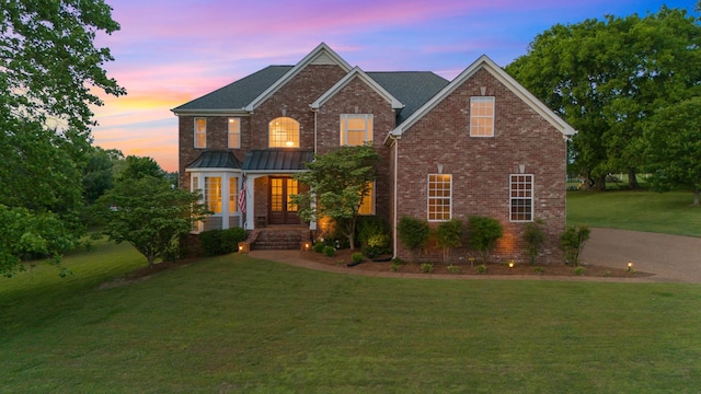 traditional-style house with brick siding, a lawn, and a porch