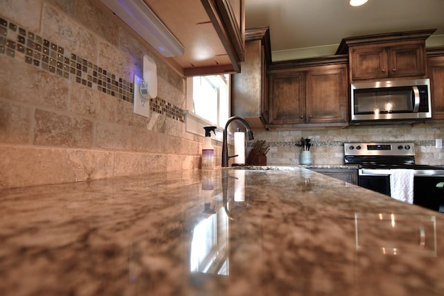 146 Neecee Dr, Smyrna, TN 37167 - kitchen with light stone countertops, a sink, stainless steel appliances, decorative backsplash, and dark brown cabinetry
