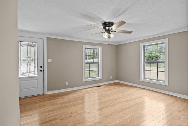 spare room with a textured ceiling, baseboards, light wood-style floors, a ceiling fan, and crown molding