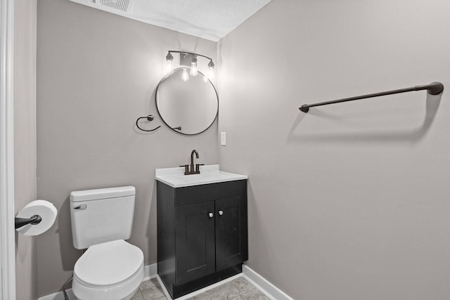 half bathroom with a textured ceiling, vanity, toilet, and baseboards