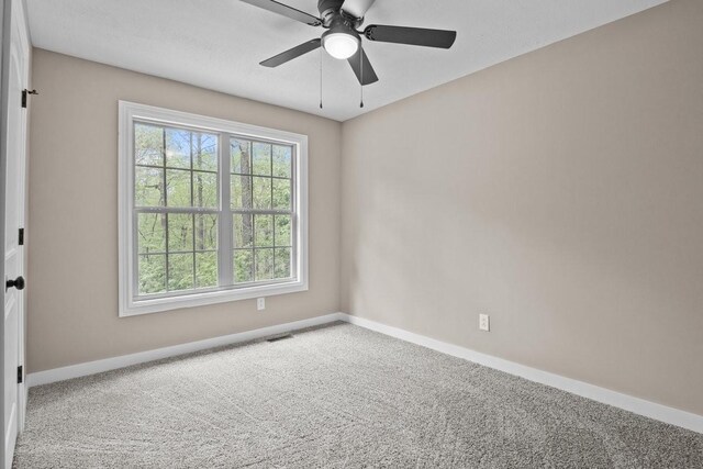 spare room featuring visible vents, a ceiling fan, baseboards, and carpet floors