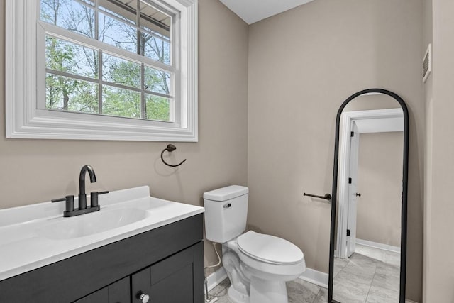 bathroom featuring toilet, vanity, marble finish floor, baseboards, and visible vents